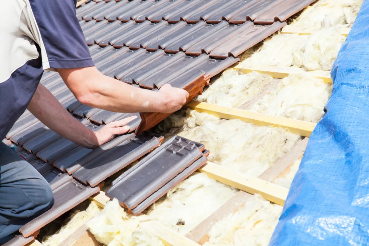a roofer laying tiles on the roof