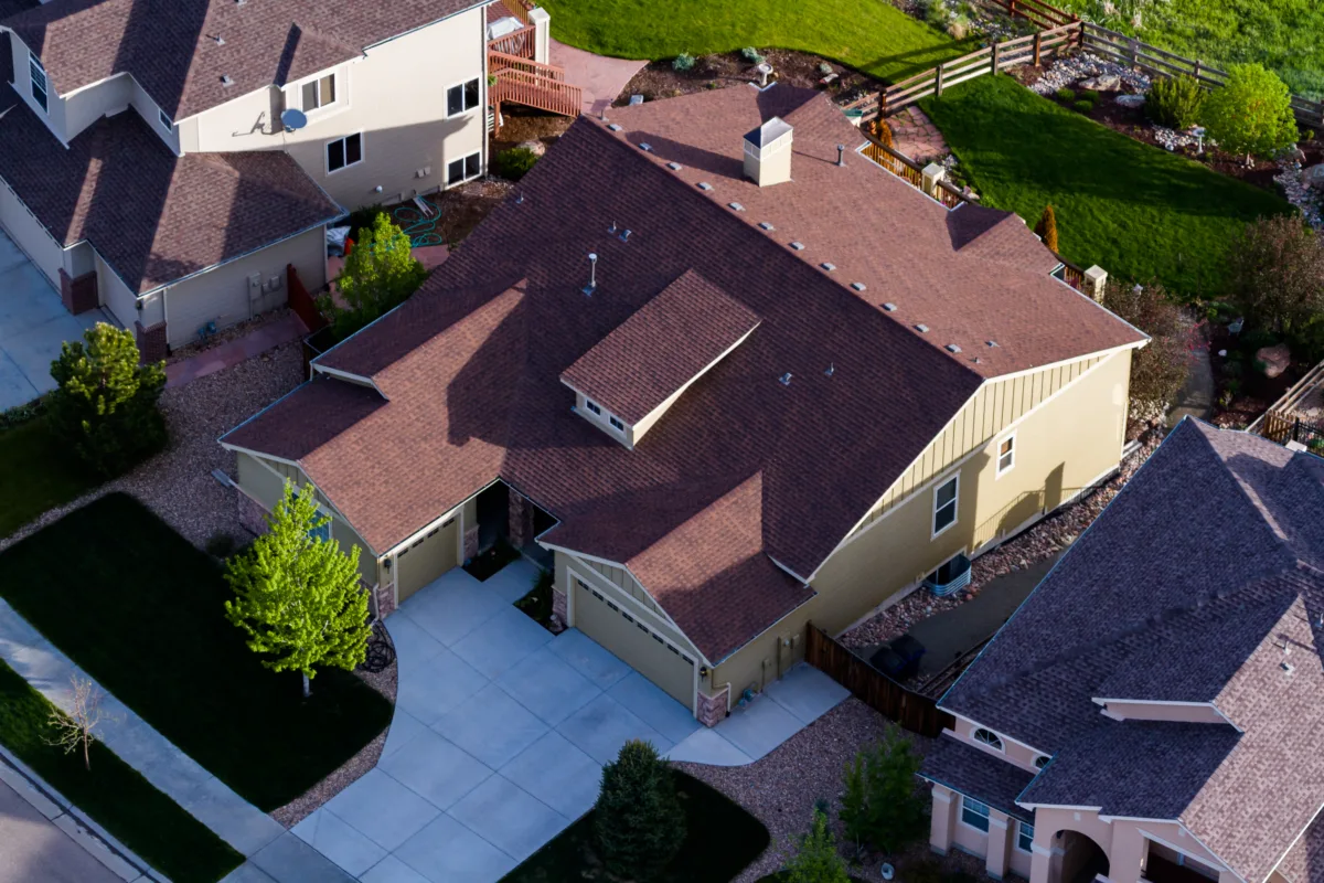 Aerial view of a residential home with brown asphalt shingles and modern roofing design.