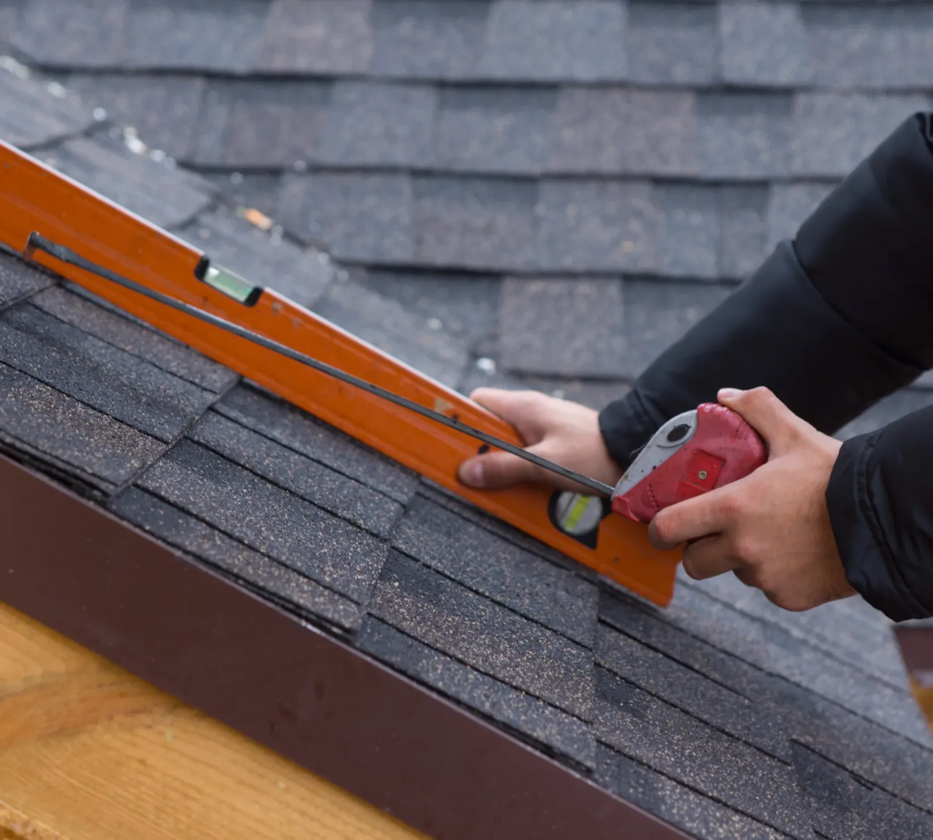 Roofer holding a tape measure and level Roofer holding a tape measure and spirit level in his hands over newly installed tiles on a new build wooden house